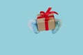 Santa Claus gives a present - gift box with red ribbon, copy space isolated on light blue. Concept for Christmas gifts Royalty Free Stock Photo