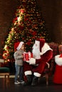 Santa Claus giving present to little boy near Christmas tree Royalty Free Stock Photo