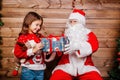 Santa Claus giving a present to a little cute girl near Christmas tree indoor Royalty Free Stock Photo