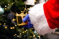 Santa Claus with gloves and face mask for Coronavirus by the Christmas tree, holding a golden present, Covid-19 and Christmas Royalty Free Stock Photo