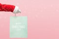 Santa Claus hand holding blue shopping bag on isolated pink background Royalty Free Stock Photo