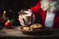 Santa Claus Hand holding a glass of milk and chocolate chip cookies an a plate Royalty Free Stock Photo