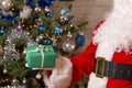 Santa Claus hands holds green gift box opposite christmas tree. Royalty Free Stock Photo