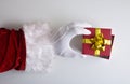 Santa Claus hands uncovering gift on white table