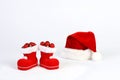 Santa Claus hat and boots with red and matt christmas balls on snow in front of white background Royalty Free Stock Photo