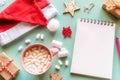 Santa claus hat, christmas decorations, coffee with marshmallows, gifts and notepad with place for text Royalty Free Stock Photo