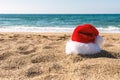 Santa Claus hat on sandy beach. Creative Christmas or New Year concept Royalty Free Stock Photo