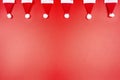 Santa Claus hats made of material arranged in a row on top, isolated on a red background. Royalty Free Stock Photo