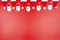 Santa Claus hats and Santa Claus faces made of material arranged in a row on top, isolated on a red background. Royalty Free Stock Photo