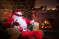 Santa Claus having a rest in a comfortable chair near the fireplace at home Royalty Free Stock Photo