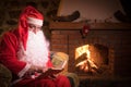 Santa Claus having a rest in a comfortable chair near the fireplace at home Royalty Free Stock Photo