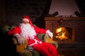 Santa Claus having a rest in a comfortable chair near the fireplace at home Royalty Free Stock Photo