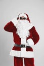 Santa Claus with headphones listening to Christmas music on light grey background Royalty Free Stock Photo