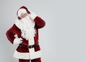 Santa Claus with headphones listening to Christmas music on light grey background. Space for text Royalty Free Stock Photo