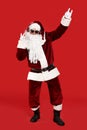 Santa Claus with headphones listening to Christmas music on red background Royalty Free Stock Photo