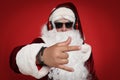 Santa Claus with headphones listening to Christmas music on red background, focus on hand Royalty Free Stock Photo