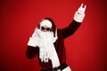 Santa Claus with headphones listening to Christmas music on red background Royalty Free Stock Photo