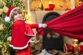 Santa Claus helper carrying big bag full of gifts. Santa helper holding a red bag with presents. Dreamy toddler on Royalty Free Stock Photo