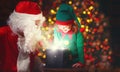 Santa Claus and helper child elf with bright magical gift in Christmas