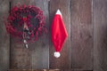 Santa Claus helper hat isolated and Christmas red berries handmande wreath on the wooden background fence