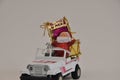 Santa Claus in his off-road, vintage car loaded with gifts and drum with the inscription, Merry Christmas