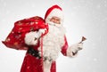 Santa Claus holding a bag with presents and ringing a bell over a white/gray background