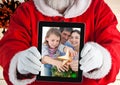 Santa claus holding a digital tablet with photo of christmas family Royalty Free Stock Photo