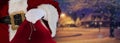 Santa claus holding his bag standing on the snow white streets with a house in the distance christmas background Royalty Free Stock Photo