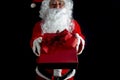 Santa claus holding a red gift box to surprise in Christmas Eve Day against black background. Christmas and Happy New Year Event Royalty Free Stock Photo