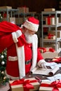 Santa Claus holding sack bag with presents gifts reading wish list. Royalty Free Stock Photo