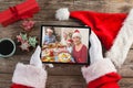 Santa claus holding tablet, making christmas video call with smiling family at dinner table Royalty Free Stock Photo