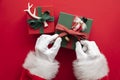 Santa Claus holding a wrapped gift box present against a red background Royalty Free Stock Photo
