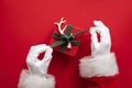 Santa Claus holding a wrapped gift box present against a red background Royalty Free Stock Photo
