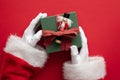 Santa Claus holding a wrapped gift box present against a red background Royalty Free Stock Photo