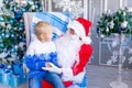 Santa Claus holds a baby in his arms near a Christmas tree in a blue Christmas interior, a happy child talks to Santa Claus Royalty Free Stock Photo