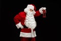 Santa Claus holds a lantern in his hand and looks into the camera on a black background. Royalty Free Stock Photo