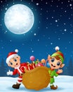 Santa claus kid with cartoon elf and a sack full of gifts in the winter night background Royalty Free Stock Photo