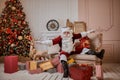 Santa Claus lay down to rest on the sofa with a bunch of gifts near the fireplace and christmas tree . New year and Merry Royalty Free Stock Photo