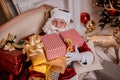 Santa Claus lay down to rest on the sofa with a bunch of gifts near the fireplace and christmas tree . New year and Merry Royalty Free Stock Photo