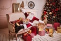 Santa Claus lay down to rest on the sofa with a bunch of gifts near the fireplace and christmas tree . New year and Merry Royalty Free Stock Photo