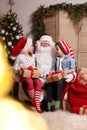 Santa Claus and little children with presents in room decorated for Christmas Royalty Free Stock Photo