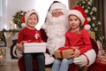 Santa Claus and little children with presents in room decorated for Christmas Royalty Free Stock Photo