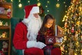 Santa Claus with a little cute girl open magical gift box in the room. Christmas time Royalty Free Stock Photo