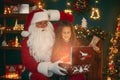 Santa Claus with a little cute girl open magical gift box in the room. Christmas time