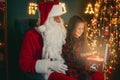 Santa Claus with a little cute girl open magical gift box in the room. Christmas time Royalty Free Stock Photo