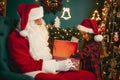 Santa Claus with a little cute girl open magical gift box in the room. Christmas time Royalty Free Stock Photo