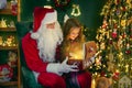 Santa Claus with a little cute girl open magical gift box in the room. Christmas time