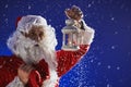 Santa Claus with a long white beard holds a lamp with a candle against a blue sky. It is snowing. Christmas Royalty Free Stock Photo