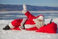 Santa Claus lying on the snow, looking at laptop news Royalty Free Stock Photo