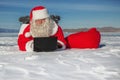 Santa Claus lying on the snow, looking at laptop news Royalty Free Stock Photo